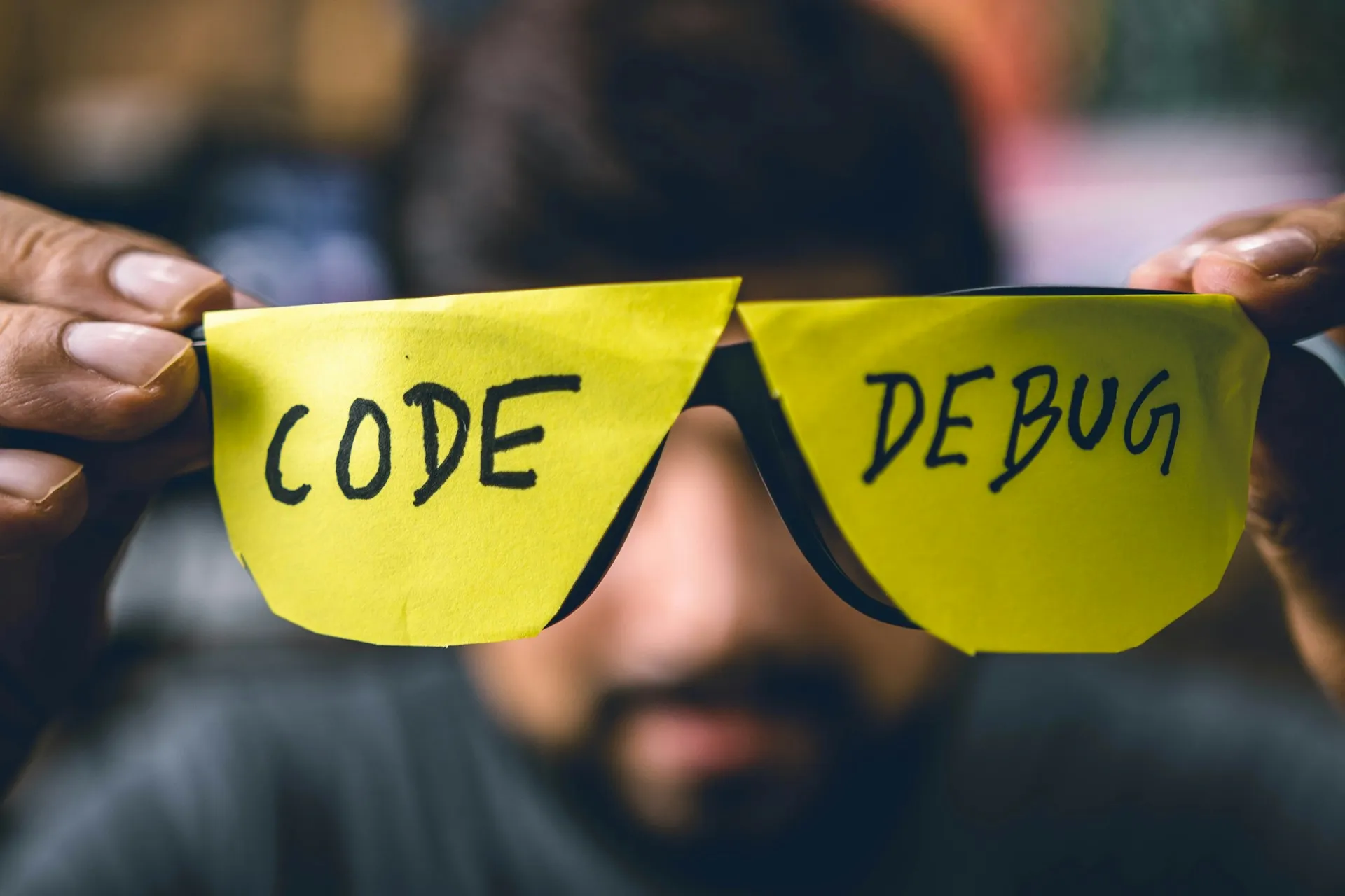 Hands holding novelty glasses with CODE and DEBUG written on lenses